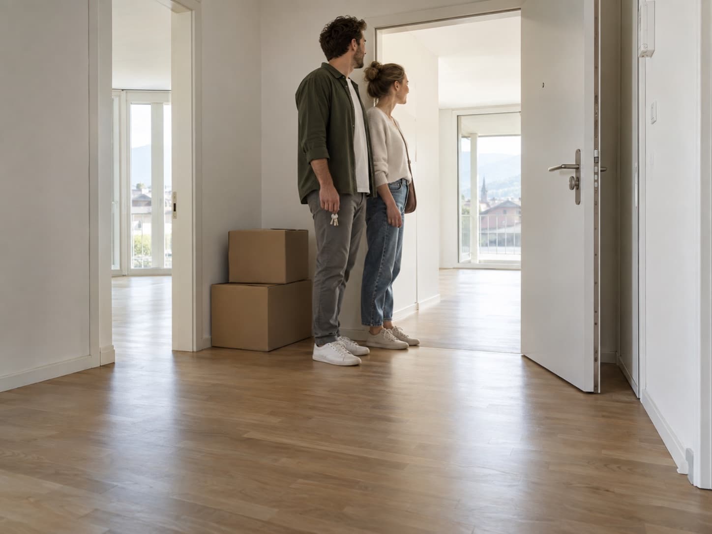 Un couple découvre un logement encore vide, des cartons près de la porte.